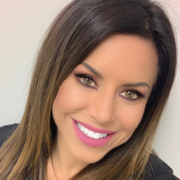 Woman with long brown hair and pink lipstick against a plain background