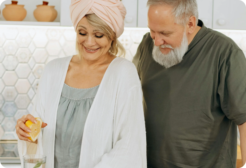 Man and woman in a kitchen setting, with the woman holding a container.
